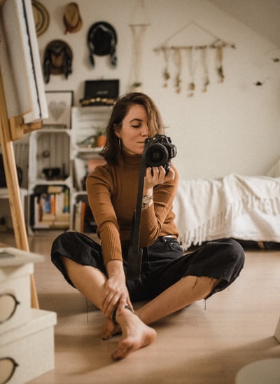 Sitting on a brown wood floor with SLR cameras, black woman
